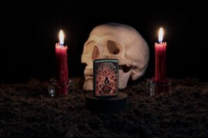 Lifestyle image of Spider Design Texture Print Black Matte Windproof Lighter standing with a skull and lit candles behind it.