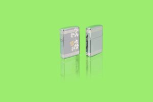 Lifestyle image of two Zippo Laser 360° Clover Design High Polish Chrome Pocket Lighters standing in a green scene.