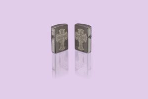 Glamour shot of two Zippo Laser Engraved Celtic Cross Design Black Ice Windproof Lighters, standing in a purple scene.