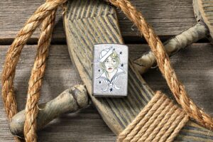 Lifestyle image of Sailor Girl Tattoo Design Street Chrome™ Windproof Lighter laying on a ships helm with rope around it.